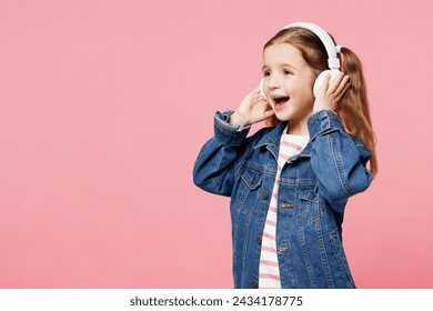 Little child cute kid girl 7-8 years old wears denim shirt listen to music in headphones look aside on area isolated on plain pastel light pink background. Mother's Day love family lifestyle concept - Powered by Shutterstock