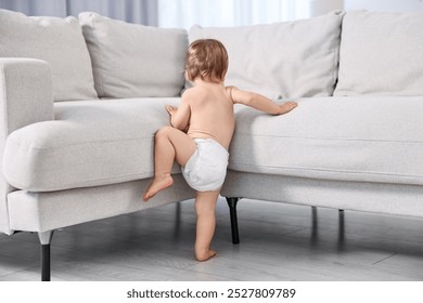 Little child in diaper climbing on sofa at home, back view - Powered by Shutterstock