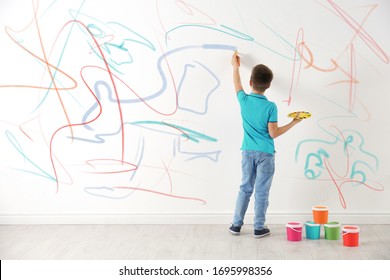 Little Child Drawing Scribbles On White Wall Indoors