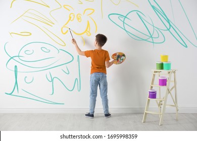 Little Child Drawing Scribbles On White Wall Indoors