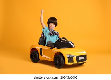 Little Child Driving Toy Car On Yellow Background