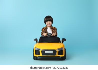 Little Child Driving Yellow Toy Car On Light Blue Background