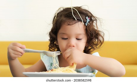 Little Child Enjoys Eating Spagetti By Herself. 