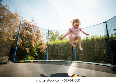 Little child enjoys jumping on trampoline - outside in backyard