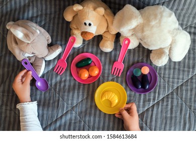 Little Child Feeding Her Stuffed Toys At Home. Children Games At Home.