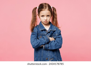 Little child frowning sad fun kid girl 7-8 years old wears denim shirt hold hands crossed folded look camera isolated on plain pastel light pink background. Mother's Day love family lifestyle concept