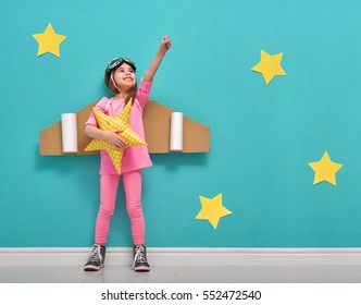 Little child girl in an astronaut costume is playing   dreaming becoming spaceman  Portrait funny kid background bright blue wall and yellow stars 
