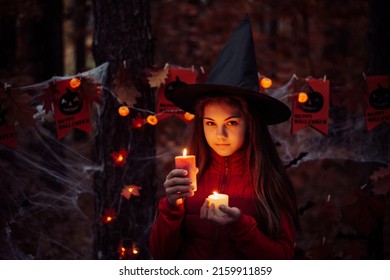 Little Child Girl With Burning Candles In Dark Forest. Witch Concept, Spooky Atmosphere, Halloween Decorations