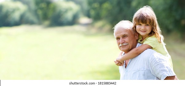 Little child girl hugs grandpa On Walk in the summer outdoors. Concept of friendly family. copy space. banner
