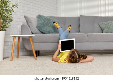 Little Child Girl Looking At Digital Tablet. Kid Enjoying Tablet At Home