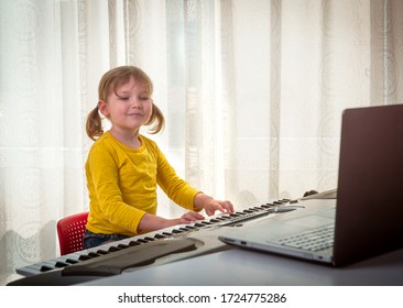 Little child girl playing the piano. Online music lesson with teacher by laptop
