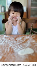 Little Child Girl Sitting At Table And Playing With Dough And Flour 