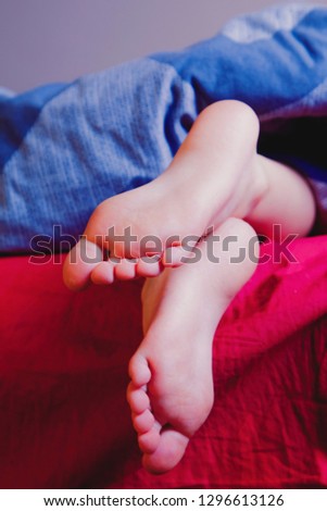 Little child girl sleeping in bed at home. Feet under the blanket on her bed on bedroom. Sleep and relax concept.