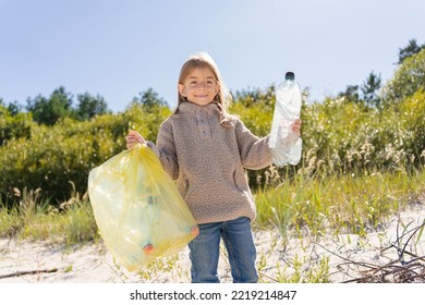 Little Child Girl Sorting Plastic Bottle Into The Trash Bag At The Beach. Ecology And Environment Concept.