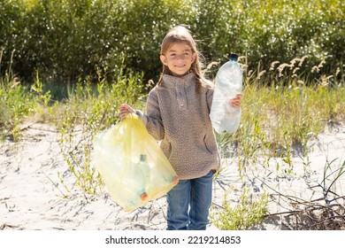 Little Child Girl Sorting Plastic Bottle Into The Trash Bag At The Beach. Ecology And Environment Concept.