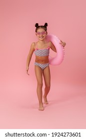 Little Child Girl In Swimwear With Inflatable Rubber Ring Running On Pink Background