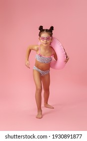 Little Child Girl In Swimwear With Rubber Ring Running On Pink Background