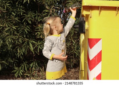 Little Child Girl Throw Plastic Bottle In The Yellow Trash Bin