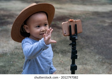 Little Child Girl Wears Hat, Using Video Call From Cell Phone And Waving Hand To Someone