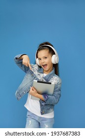 Little Child Girl In White Headphones Shows At Digital Tablet