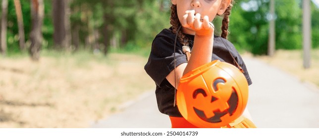 Little child girl in witch costume holding jack-o-lantern pumpkin bucket with candies and sweets. Kid trick or treating in Halloween holiday - Powered by Shutterstock