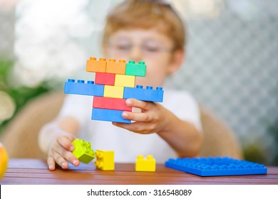 Little Child With Glasses Playing With Lots Of Colorful Plastic Blocks Indoor. Kid Boy Having Fun With Building And Creating. Selective Focus On Toy