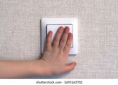 Little Child Hand Turning On The Light With A Wall Switch