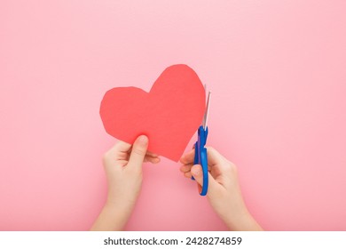 Little child hands holding scissors and cutting red heart shape from application paper on light pink table background. Pastel color. Making decoration elements. Closeup. Point of view shot. - Powered by Shutterstock