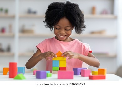 Little child happy african american girl with bushy hair playing with colorful wooden blocks and smiling, enjoying table games while visiting psychologist or playing alone at home, closeup - Powered by Shutterstock