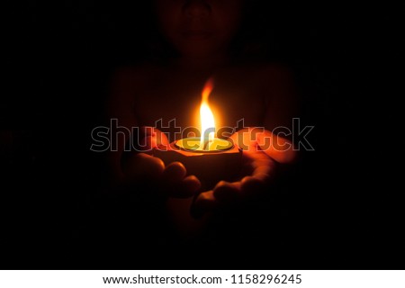 Little child holding burning candle in darkness with noise and grain effect.