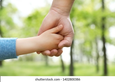 Little child holding hands with his father outdoors, closeup. Family time