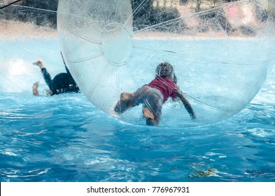 Little child inside the inflatable ball floating on water in swimming pool