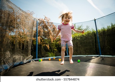 Little child jumping on big trampoline - outdoor in backyard