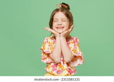 Little child kid girl 6-7 years old wears casual clothes point on princess diadem have fun close eyes hold face isolated on plain pastel green background. Mother's Day love family lifestyle concept - Powered by Shutterstock