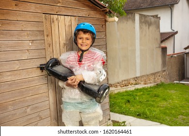 Little Child Kid With Hoverboard And Overprotective Mother Keeping A Boy In Bubble Wrap About To Go Riding Super Safe