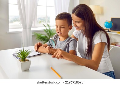 Little Child Learning New Things With Mother Or Teacher. Happy School Boy Together With Mom Or Tutor Sitting At Desk With Pencil And Notebook And Investigating Something Small Through Magnifying Glass