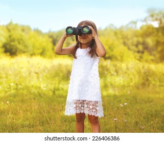 Little Child Looks In Binoculars Outdoors In Sunny Summer Day