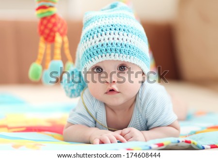 little child lying on a children's rug in the white-blue cap. Small Depth of Field (DOF) 