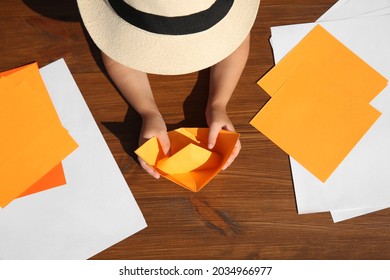 Little Child Making Paper Boat At Wooden Table, Top View