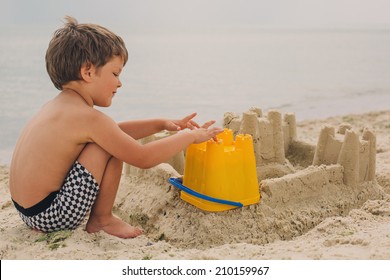 Little Child Making Sand Castles At The Beach