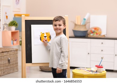 Little child painting on easel in room - Powered by Shutterstock