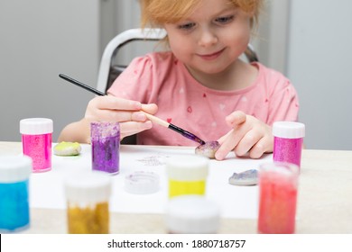 Little Child Painting Pebbles With Colorful Paints On The Table