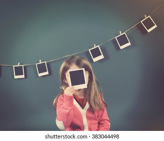 A Little Child Photographer Is Holding Up A Photo Of A Blank Film Print And Other Photos On The Wall For A Art Or Creativity Concept.