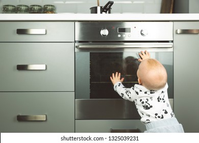 Little Child Playing With Electric Stove In The Kitchen. Baby Safety In Kitchen