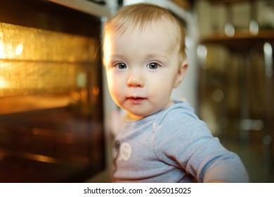 Little Child Playing With Electric Stove In The Kitchen. Toddler Boy Near Hot Oven. Baby Safety In Kitchen.