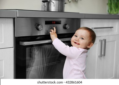 Little Child Playing With Electric Stove In The Kitchen