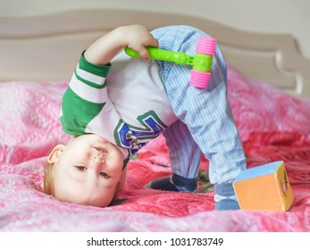 little child playing on the bed, standing on his head upsidedown. close up portrait