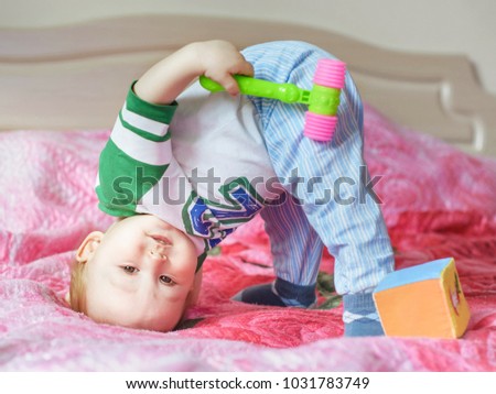 little child playing on the bed, standing on his head upsidedown. close up portrait