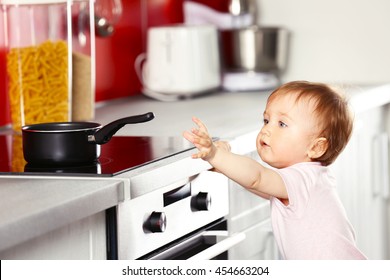 Little child playing with pan and electric stove in the kitchen