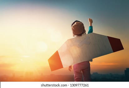 Little child playing pilot. Girl on the background of sunset sky. Kid in an astronaut costume dreaming of becoming a spaceman.